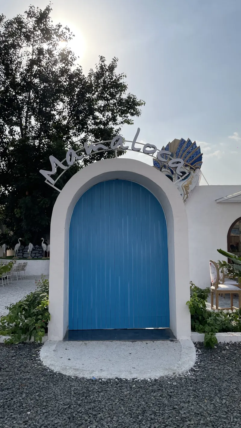 The blue arched door at the entrance, with the Mama Loca sign and mask above it
