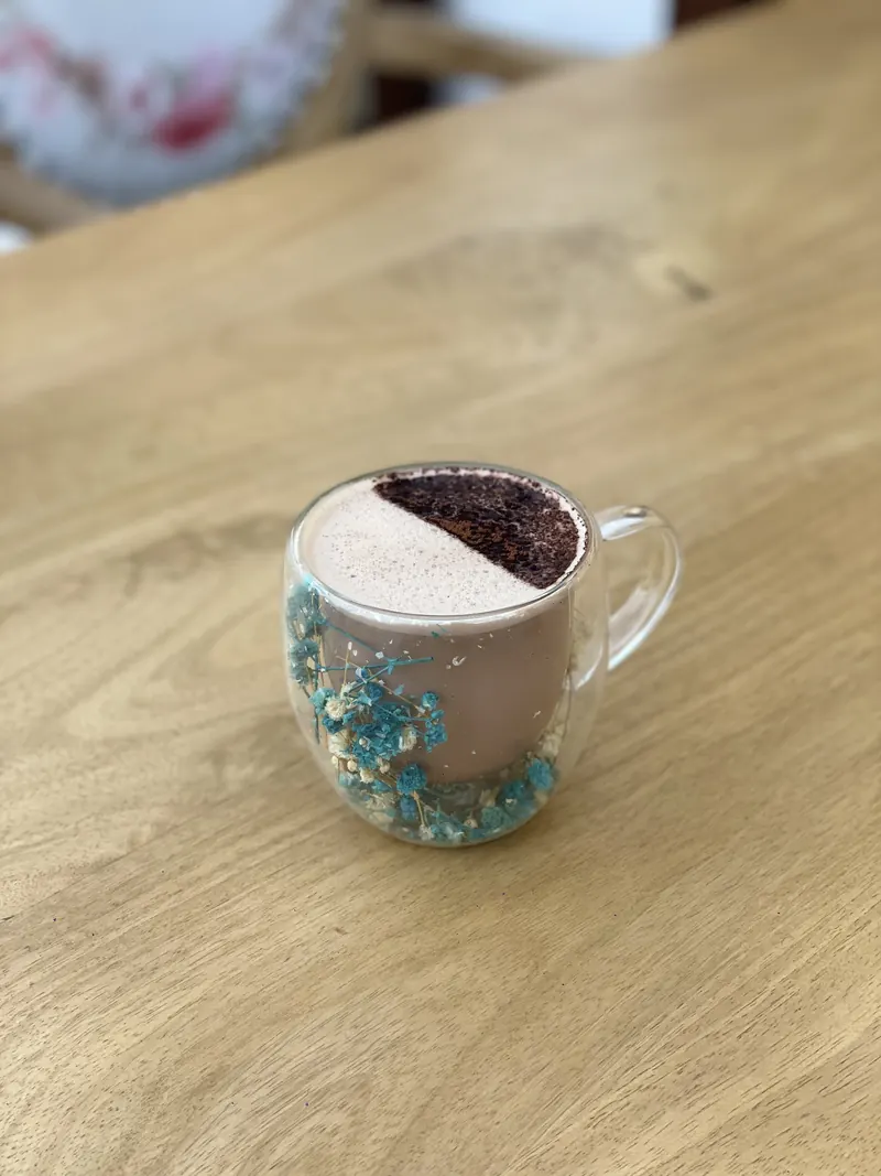 A mocha in a glass cup, half dusted with cocoa