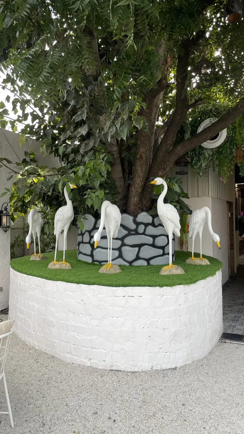 White heron sculptures around the old tree in the garden