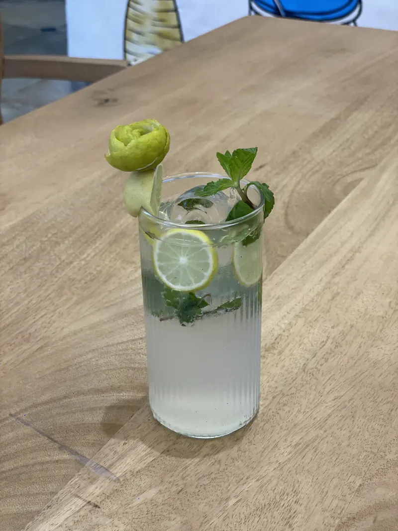 A lime mojito in a ribbed glass, with a cucumber rose