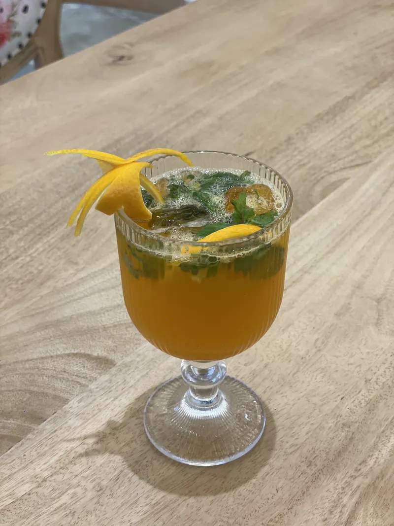 A mango cooler in a footed coupe, with an orange twist